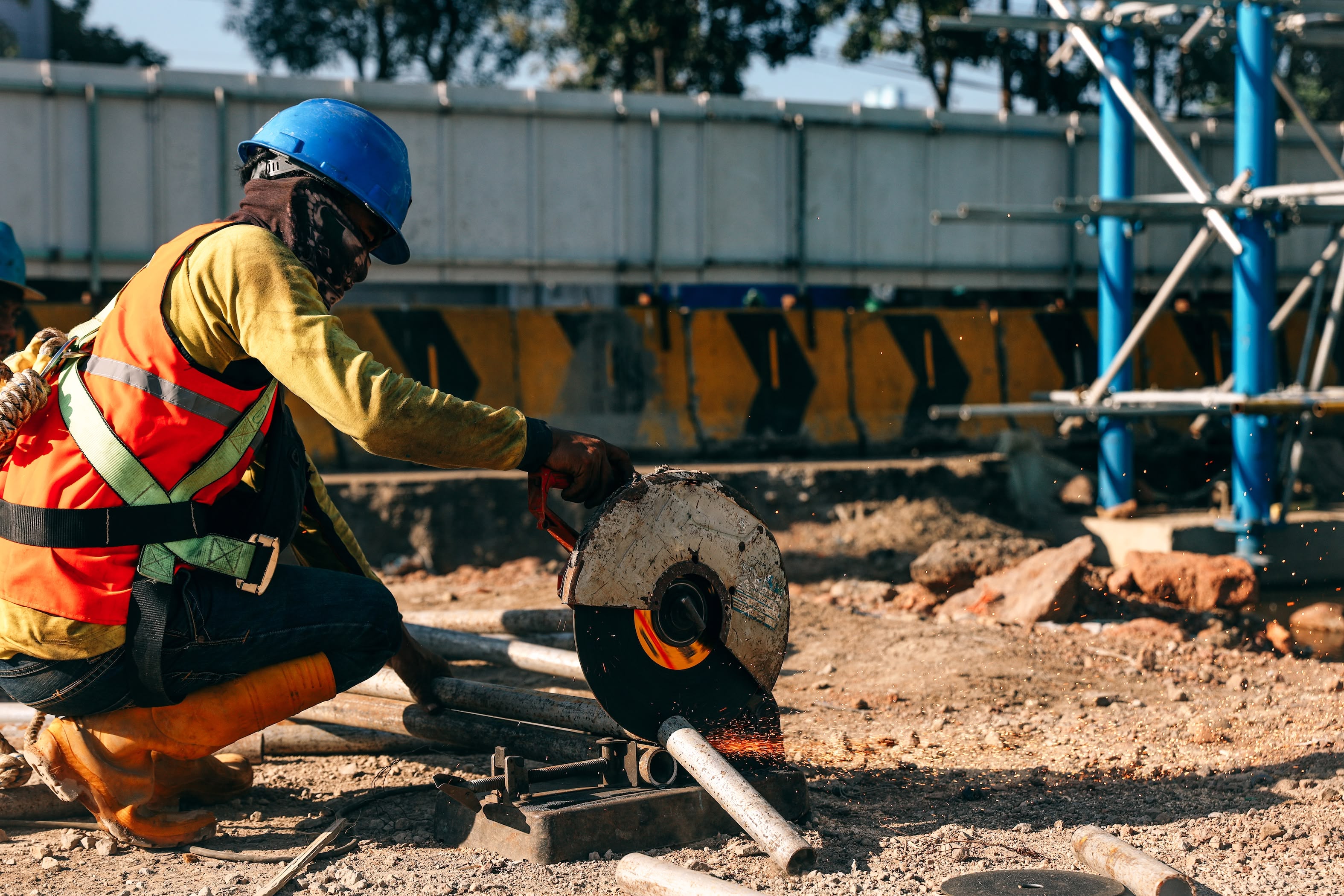 Construction worker cutting metal pipe with an angle grinder