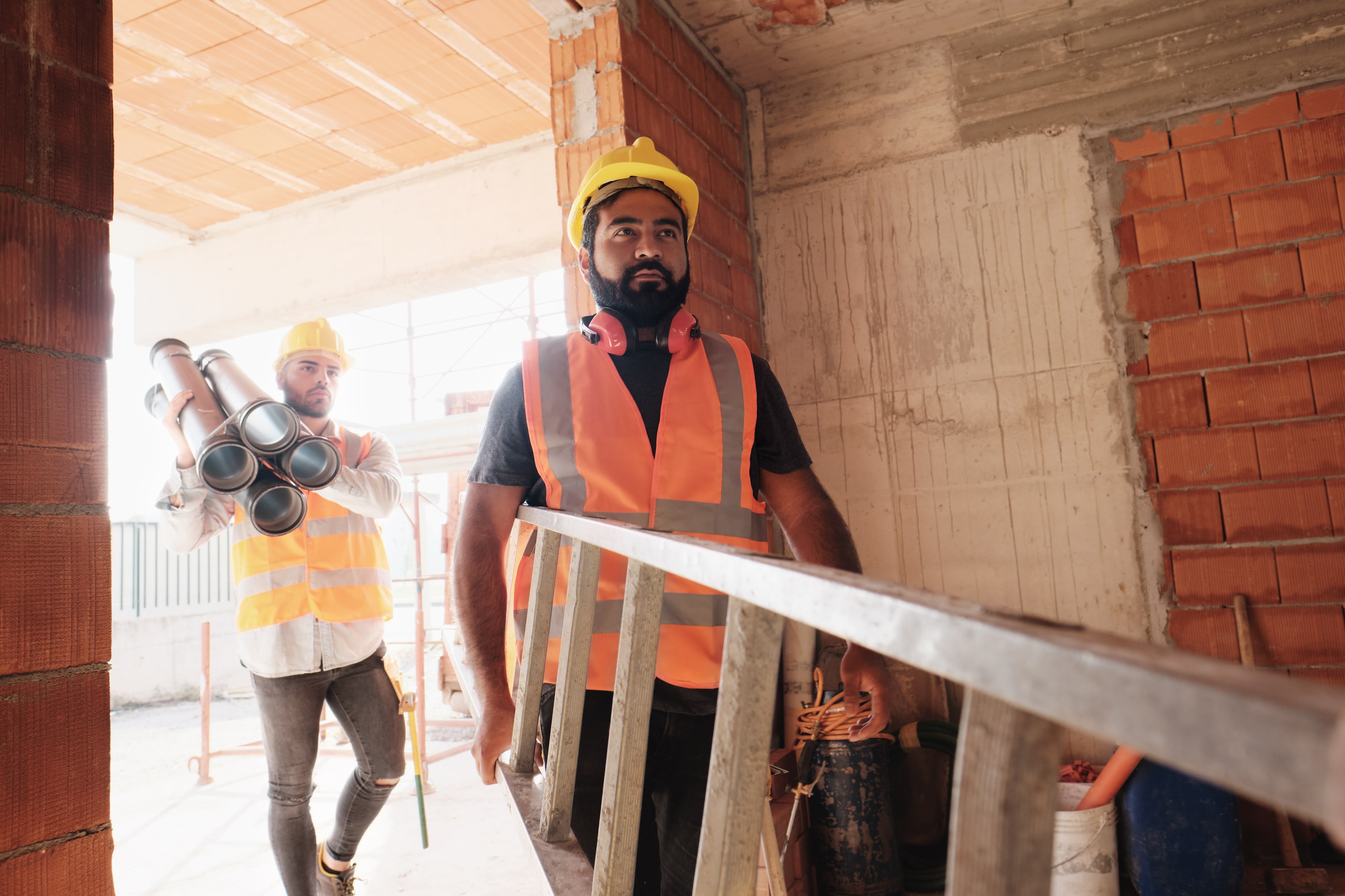 Construction workers on a jobsite carrying a ladder